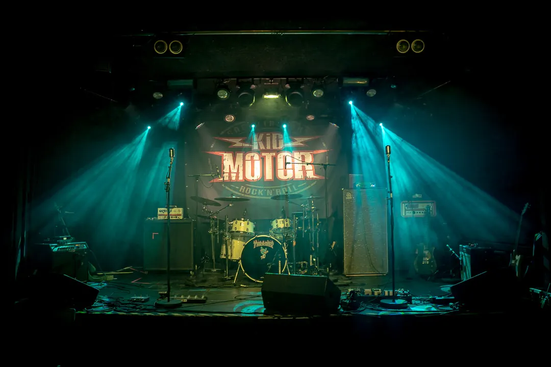 Bühne von Kid Motor vor dem Konzert: Schlagzeug, Verstärker und Mikrofone vor dem Backdrop