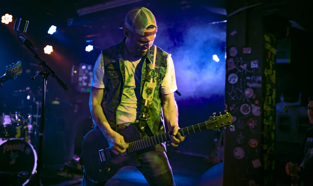 Gitarrist von Kid Motor live im blauen Licht, im Hintergrund Schlagzeug und Bühnennebel